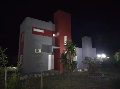 a house with a red and white building at night at EL REFUGIO DE MERLO, alquiler temporario in Merlo