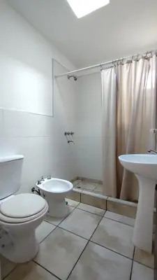 a white bathroom with a toilet and a sink at EL REFUGIO DE MERLO, alquiler temporario in Merlo