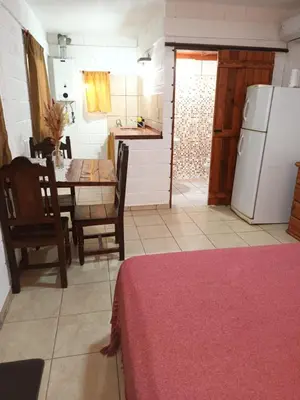 a kitchen and dining room with a table and a refrigerator at Cabañas El Nogal in Villa Anizacate