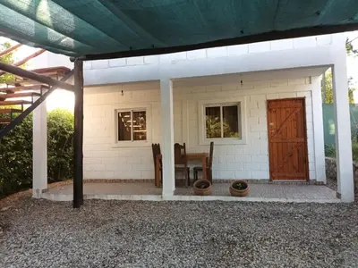 a small white house with a table and a door at Cabañas El Nogal in Villa Anizacate