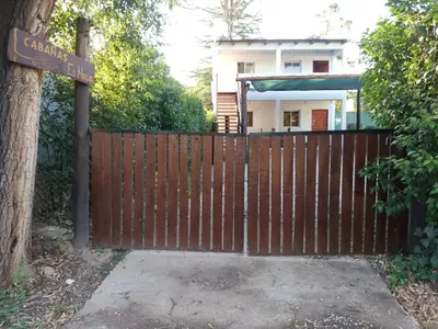 a wooden fence with a sign in front of a house at Cabañas El Nogal in Villa Anizacate