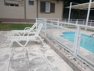 two white chairs sitting next to a swimming pool at Departamento Matrimonial Merlo San luis in Merlo