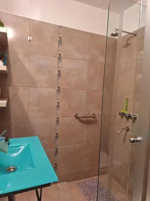a shower with a glass door next to a blue sink at El Abrojal 4 - Monoambiente Céntrico, zona Patio Olmos in Cordoba