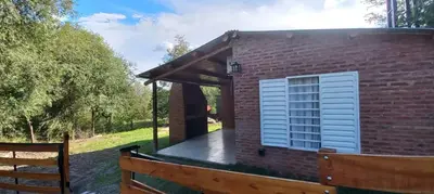 a small brick house with a porch and a wooden fence at Cabaña Don Leonardo in Santa Rosa de Calamuchita
