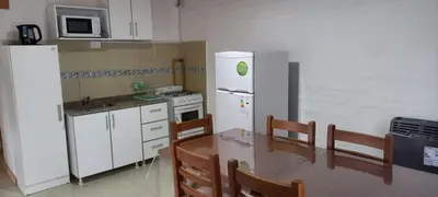 a kitchen with a white refrigerator and a table with chairs at Cabaña Don Leonardo in Santa Rosa de Calamuchita
