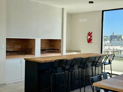 a kitchen with a bar with black bar stools at Departamento moderno pleno centro con pileta y cochera privada in Villa Carlos Paz