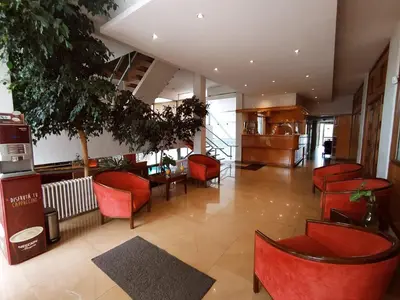 a lobby with red chairs and tables in a building at Gran Lourdes Hotel in Villa Carlos Paz
