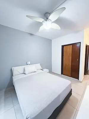 a bedroom with a white bed and a ceiling fan at Gran Lourdes Hotel in Villa Carlos Paz