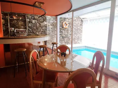 a dining room with a table and a swimming pool at Gran Lourdes Hotel in Villa Carlos Paz