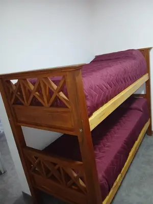 a wooden bunk bed with purple sheets on it at santa rita 2 in Cordoba