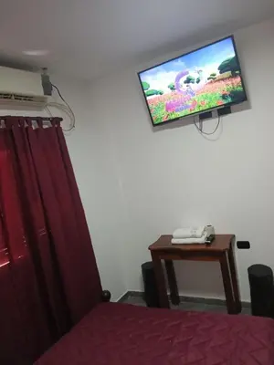 a room with a tv on the wall with a bed and a table at santa rita 2 in Cordoba