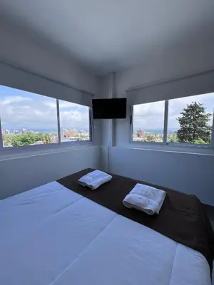 a white bedroom with a bed with two towels on it at Astoria Hotel in Villa Carlos Paz