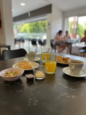 a table with plates of food and glasses of orange juice at Astoria Hotel in Villa Carlos Paz