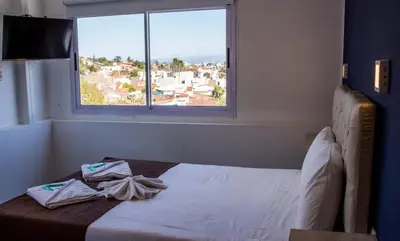 a bedroom with a bed and a window with a view at Astoria Hotel in Villa Carlos Paz