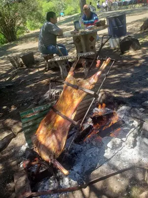 a piece of meat is cooking over a fire at Rincon de la Selva in La Calera