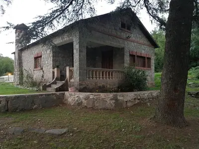 an old stone house with a tree in front of it at Rincon de la Selva in La Calera