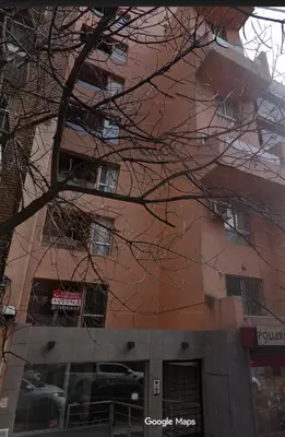 a tall pink building with a tree in front of it at Pent House Nueva Córdoba in Cordoba
