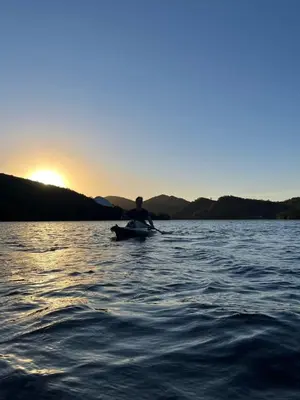 a person in a boat on a lake at sunset at Monte Adentro in Dique Nivelador