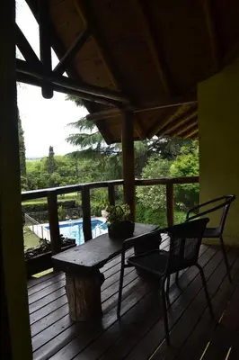 a wooden deck with a table and two chairs on it at Posada La Lucía in Villa General Belgrano