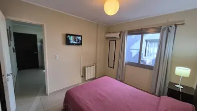 a bedroom with a pink bed and a window at Departamento pleno centro Carlos Paz con pileta in Villa Carlos Paz
