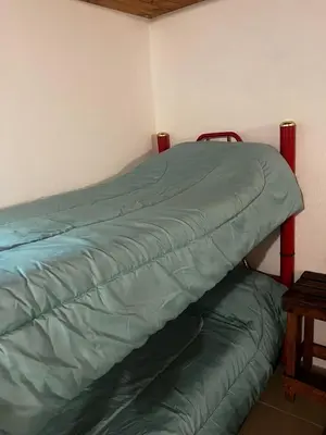 a bed with a green comforter in a room at Complejo Monarcas in Villa Carlos Paz