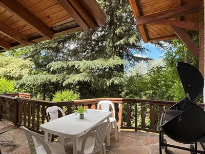a white table and chairs on a wooden deck at Casa Familiar in La Cumbrecita
