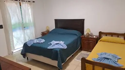 a bedroom with a bed with blue sheets and a window at Bosquesito in Mina Clavero