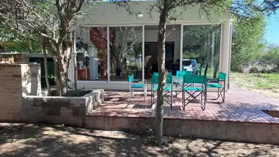 a group of chairs and tables in front of a house at Bosquesito in Mina Clavero