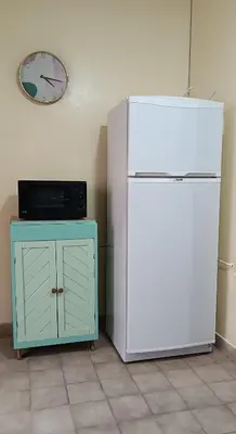 a white refrigerator next to a cabinet and a clock at Grivia in Cordoba