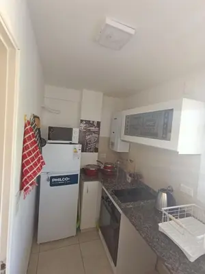 a small kitchen with a refrigerator and a sink at Departamento moderno y luminoso in Cordoba