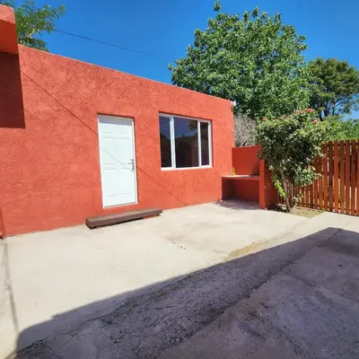a red building with a white door and a fence at Cielo Azul in Santa Rosa de Calamuchita
