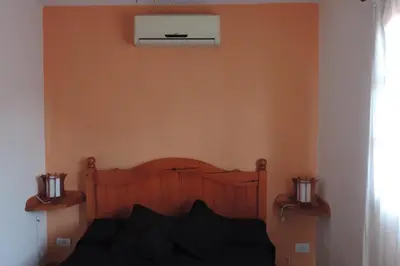 a bedroom with a wooden bed with a air conditioner on the wall at Cielo Azul in Santa Rosa de Calamuchita