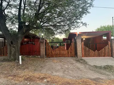 a house with a wooden fence and a tree at Cielo Azul in Santa Rosa de Calamuchita