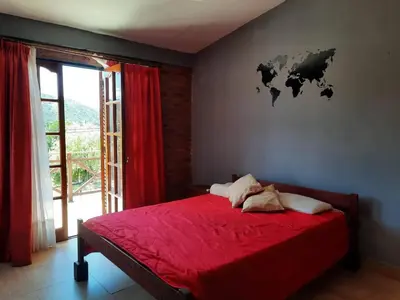a bedroom with a red bed with a world map on the wall at Rincón Serrano in Villa Carlos Paz