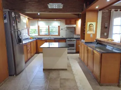 a kitchen with wooden cabinets and a stainless steel refrigerator at Rincón Serrano in Villa Carlos Paz