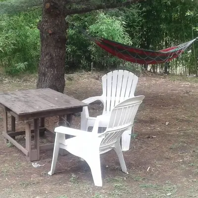 two white chairs and a wooden table and a hammock at Playa Hostel in Santa Rosa de Calamuchita