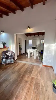 a living room with a white table and wooden floors at Playa Hostel in Santa Rosa de Calamuchita