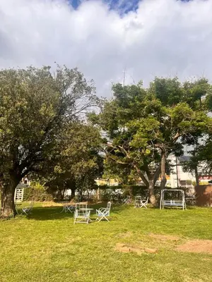 a group of white chairs in a field with trees at Hotel Mundial in Merlo