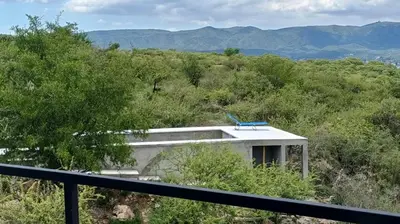 a building on a hill with mountains in the background at El Descanso in Villa Santa Cruz del Lago