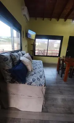 a couch sitting in a living room with two windows at Cabaña Cina Cina in Villa Larca