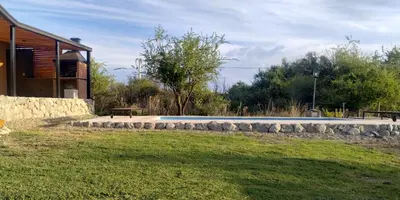 a swimming pool with a stone wall next to a house at Cabaña Cina Cina in Villa Larca