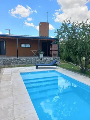 a swimming pool in front of a house at Cabaña Cina Cina in Villa Larca