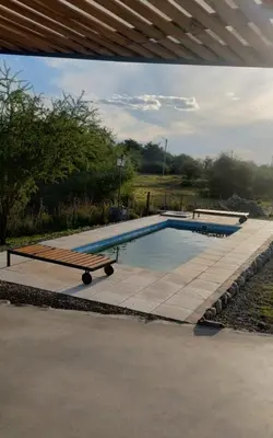 a swimming pool with a wooden bench next to it at Cabaña Cina Cina in Villa Larca