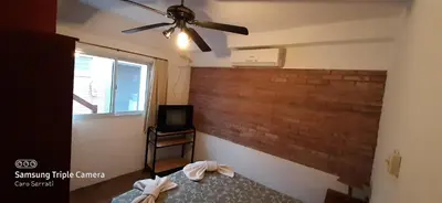 a bedroom with a ceiling fan and a brick wall at Hosteria Arture in Villa Cura Brochero