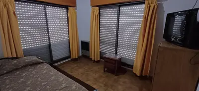 a bedroom with two large windows with yellow curtains at Hosteria Arture in Villa Cura Brochero