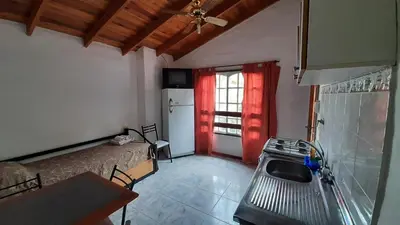 a room with a bed and a kitchen with a refrigerator at Hosteria Arture in Villa Cura Brochero