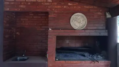 a brick fireplace with a sink and a clock at Chalet Arredondo Villa Carlos Paz in Villa Carlos Paz