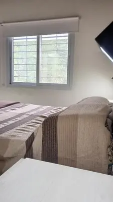 two beds in a bedroom with a window at Chalet Arredondo Villa Carlos Paz in Villa Carlos Paz