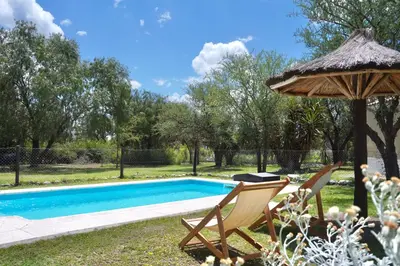 a swimming pool with two chairs and an umbrella at El Cardal in Merlo