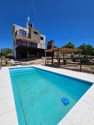 a blue swimming pool in front of a house at Casa en flor serrana in Cavalango